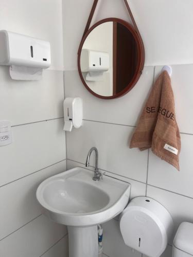 a white bathroom with a sink and a mirror at Apto ao lado do Shopping Caruaru próximo ao pátio unidade 302 in Caruaru