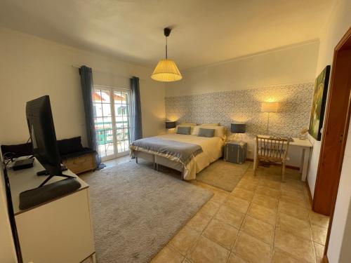 a bedroom with a bed and a flat screen tv at MHouse lease Comporta Nature Retreat 3BR Villa in Comporta