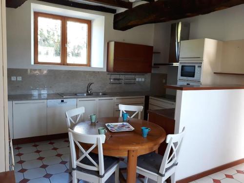 a kitchen with a wooden table and white chairs at Gite TY KERMORZU in Saint-Adrien
