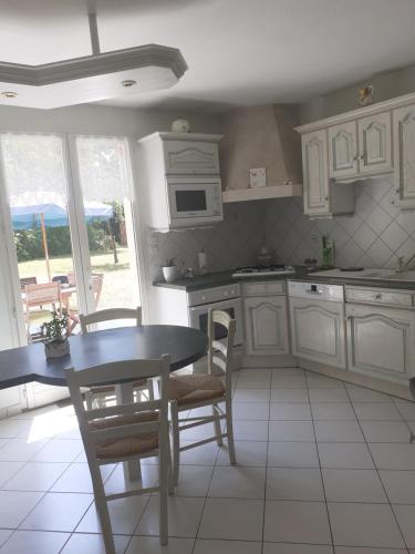 een keuken met witte kasten en een tafel en stoelen bij Evènements le Mans et sa région in Challes