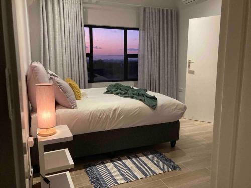 a bedroom with a bed and a large window at Urban Awe Apartment: Sarona City in Gaborone