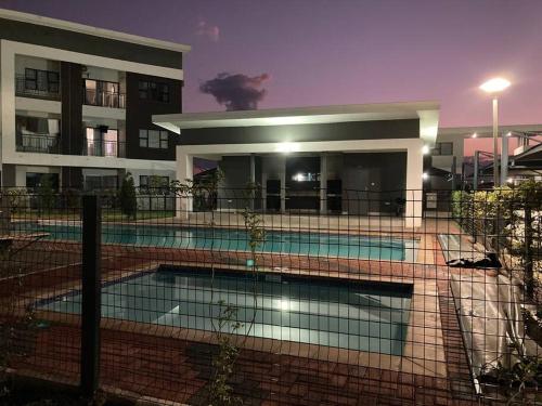 a building with a swimming pool in front of a building at Urban Awe Apartment: Sarona City in Gaborone
