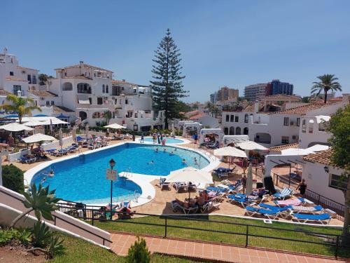 a large swimming pool with chairs and umbrellas at Apart Aleire Pueblo Evita in Benalmádena