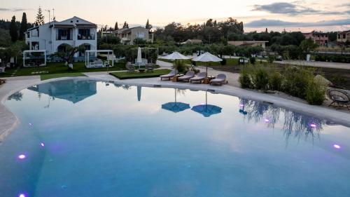 ein großer Pool mit blauem Wasser vor einem Haus in der Unterkunft Sun 'n Chill, Boutique Apartments & Beach Villa in Melíkia