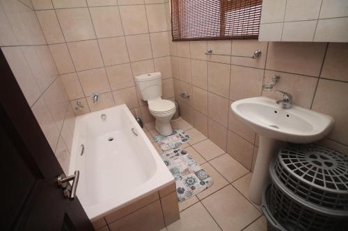 een badkamer met een bad, een toilet en een wastafel bij Topanga 70, Uvongo in Margate