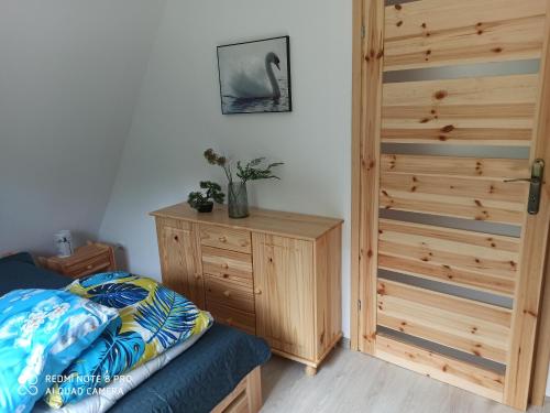 1 dormitorio con 1 cama y armario de madera en Urokliwy domek na mazurach, en Pilec