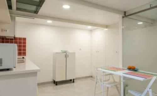 Camarate的住宿－Adelino apartamentos，厨房配有桌子和白色冰箱。