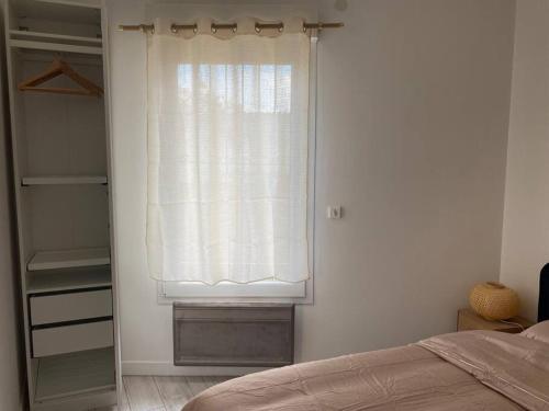 une chambre avec une fenêtre avec un rideau et un placard dans l'établissement Appartement cosy à Bordeaux, à Bordeaux