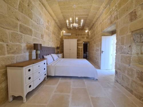 a bedroom with a white bed and a stone wall at Farmhouse Villa with Large Pool and Garden in Gozo in Għarb