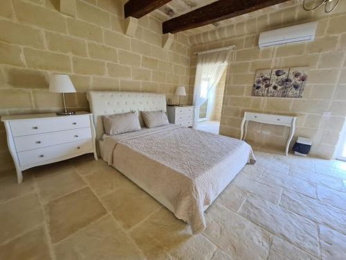 um quarto com uma cama e uma parede de pedra em Farmhouse Villa with Large Pool and Garden in Gozo em Għarb