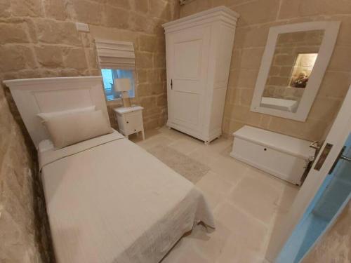 een slaapkamer met een wit bed en een wastafel bij Farmhouse Villa with Large Pool and Garden in Gozo in Għarb