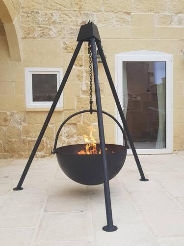 a fire pit on a patio in front of a building at Farmhouse Villa with Large Pool and Garden in Gozo in Għarb
