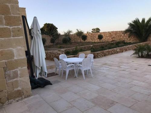a patio with a table and chairs and an umbrella at Farmhouse Villa with Large Pool and Garden in Gozo in Għarb