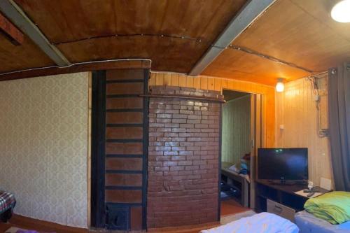 sala de estar con chimenea de ladrillo y TV en Дом на берегу Чудского озера, en Katase