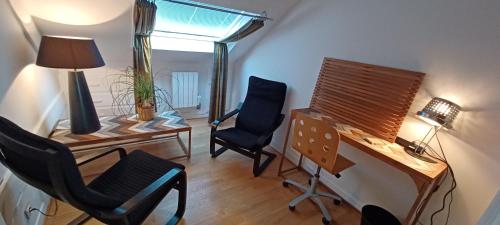 een kamer met een bureau, 2 stoelen en een lamp bij Lin et l'hôte in Préaux