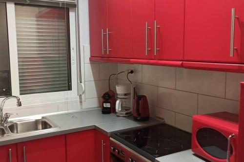 a kitchen with red cabinets and a sink at Bed and Garden in Kanoni