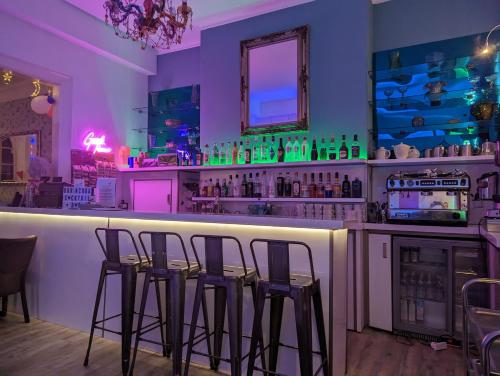 a bar with four stools at a bar with purple lighting at Acqua Beach Weymouth in Weymouth