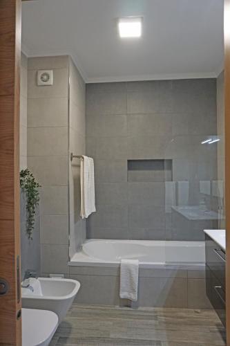 a bathroom with a tub and a toilet and a sink at Casa Gaio's in Parchal