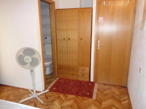 a room with a fan and a bathroom with a door at Pansion Danijela in Rogoznica