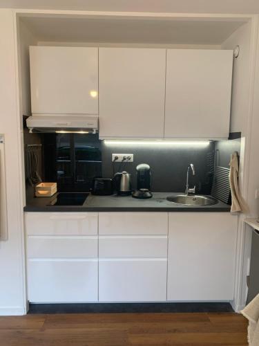 une cuisine avec des armoires blanches et un évier dans l'établissement Studio Tivoli la Tour, à Dijon