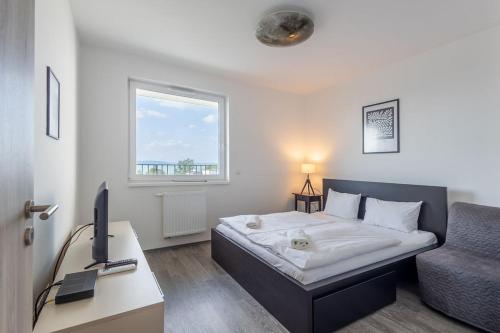 1 dormitorio con cama, escritorio y silla en LelleResort BLTN Apartmanok By BLTN, en Balatonlelle