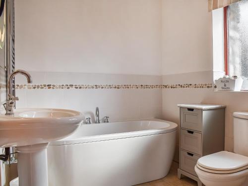een badkamer met een bad, een toilet en een wastafel bij Honeysuckle Cottage in Bishopston
