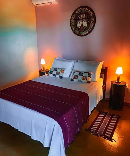 a bedroom with a large bed with two lamps at Chalés Flor de Manacá in Alto Paraíso de Goiás
