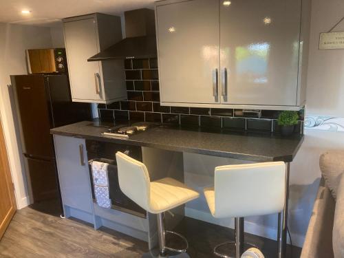 a small kitchen with a counter and two chairs at The Spinney lodge in Bubbenhall