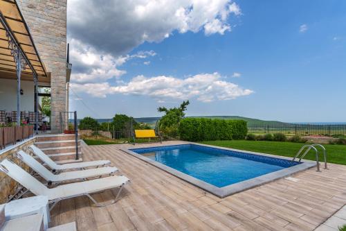 una piscina con terraza y sillas junto a una casa en Villa Poemia, en Rogachevo