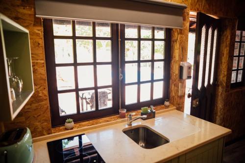 a kitchen with a sink and two windows at Quinta da Mal-disposta, cabin lodge Countryhouse in Resende