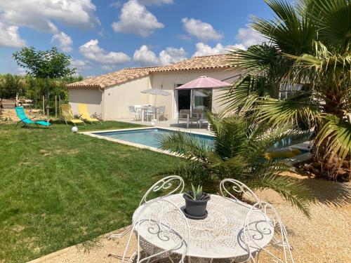 une maison avec une piscine, une table et des chaises dans l'établissement La maison aux palmiers, à Arpaillargues-et-Aureillac