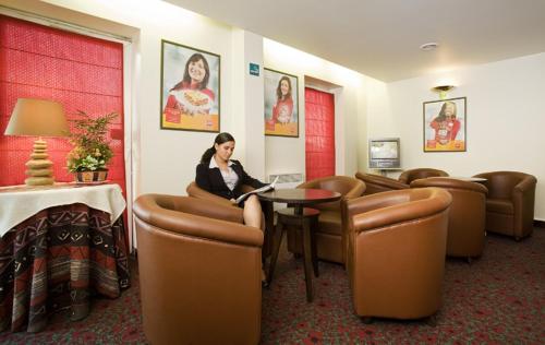 a woman sitting at a table in a waiting room at Hotel Mermoz Paris Le Bourget in La Courneuve