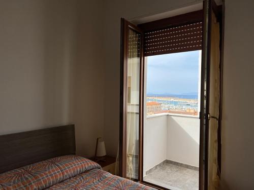 Schlafzimmer mit einem Bett und Blick auf einen Balkon in der Unterkunft Petronia Home in Porto Torres