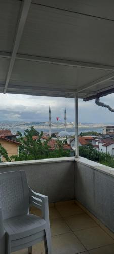 uma cadeira branca numa varanda com vista para a cidade em Lux daire em Yeniköy