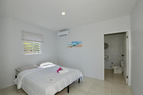 a white bedroom with a bed and a bathroom at Beach House,Villa Santirome/Free Wifi,Parking in Westpunt