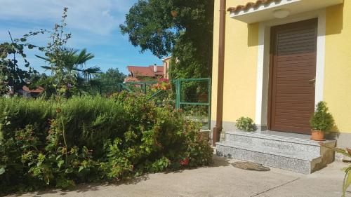 a yellow house with a wooden door and some bushes at APARTMAN ROSEMARY in Rijeka