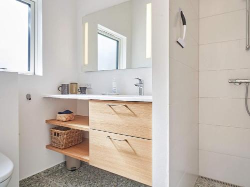 a bathroom with a sink and a toilet and a mirror at Holiday home Nexø XLI in Vester Sømarken