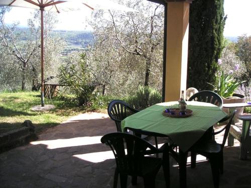 een groene tafel en stoelen op een patio bij Casa Belvedere -tranquillità tra bosco e ulivi- in Riparbella