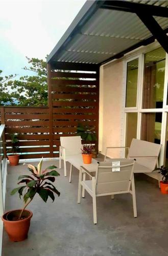 a patio with white chairs and a table and a fence at Impeccable 2-BR Apartment-Ornella Villa at Bayfront Villa in Portmore