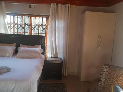 - une chambre avec un grand lit et une fenêtre dans l'établissement Nakhah Guesthouse - Private Exterior, à Witbank