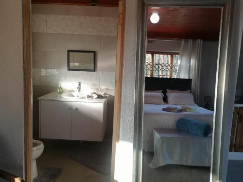 La salle de bains est pourvue d'une chambre avec un lit et un lavabo. dans l'établissement Nakhah Guesthouse - Private Exterior, à Witbank