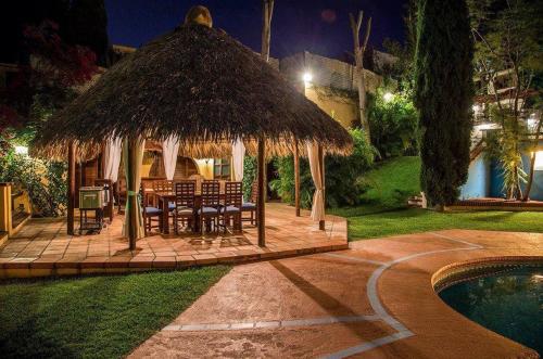 a gazebo with a table and chairs next to a pool at Hotel Casa Yunenisa in Oaxaca City