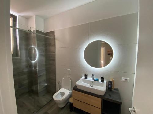 La salle de bains est pourvue d'un lavabo, de toilettes et d'un miroir. dans l'établissement Private Villa at Olea Luxury Resort, à Dhërmi