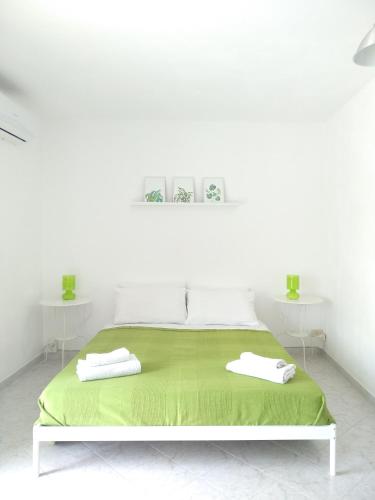 una camera bianca con un letto verde con due tavoli bianchi di Rosso di Sera Loft a Menfi