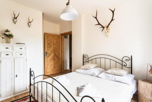 a bedroom with a bed with white sheets and antlers on the wall at Apartamenty Niebanalne - Blisko Krupówek in Zakopane