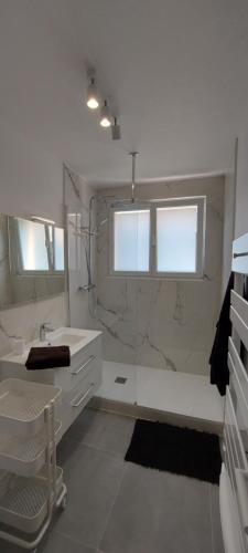 une salle de bain blanche avec un lavabo et un miroir dans l'établissement Du bonheur à la clé - T2 hyper centre, à Concarneau