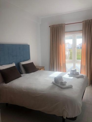 a bedroom with a large bed with towels on it at White Beach House in Praia da Areia Branca