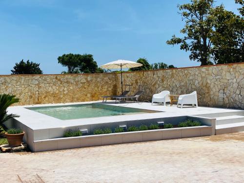 a swimming pool with two chairs and an umbrella at Villa Carmen con piscina in Siracusa