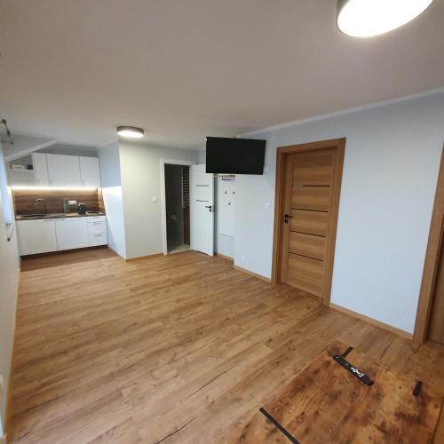 an empty living room with wooden floors and a flat screen tv at Agroturystyka Koronkowe Zacisze in Koniaków