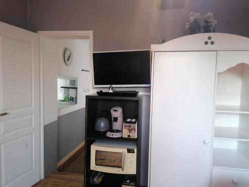 Cette chambre dispose d'une télévision et d'un four micro-ondes sur une étagère. dans l'établissement Charmant Appartement 10mn Rouen, à Franqueville-Saint-Pierre